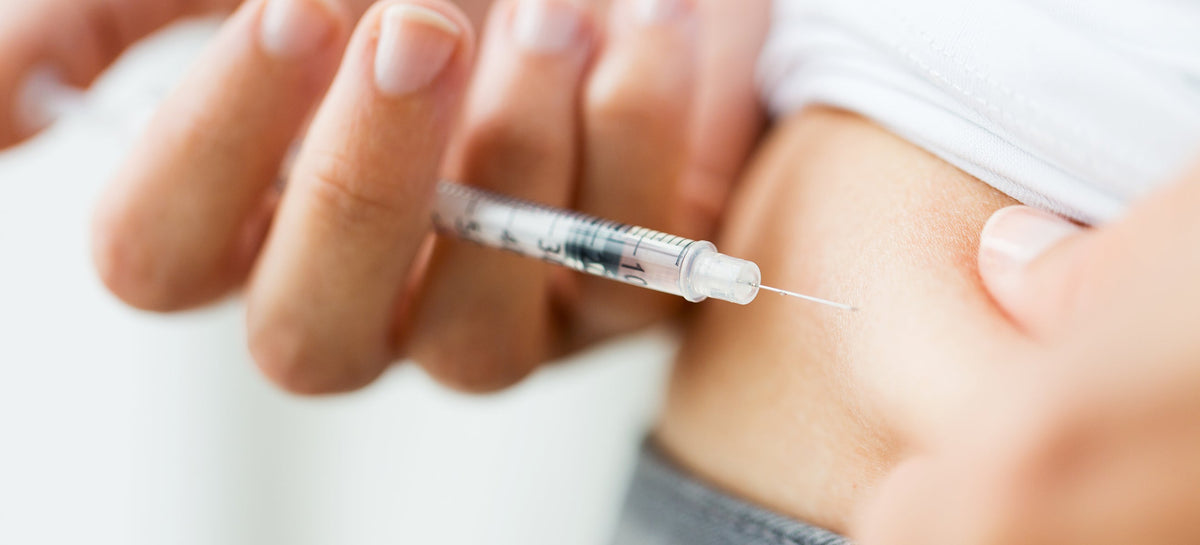 Person administering injectable medication with syringe into abdomen